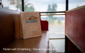 Eine Winterberger Einkaufstüte steht auf einer Bank.